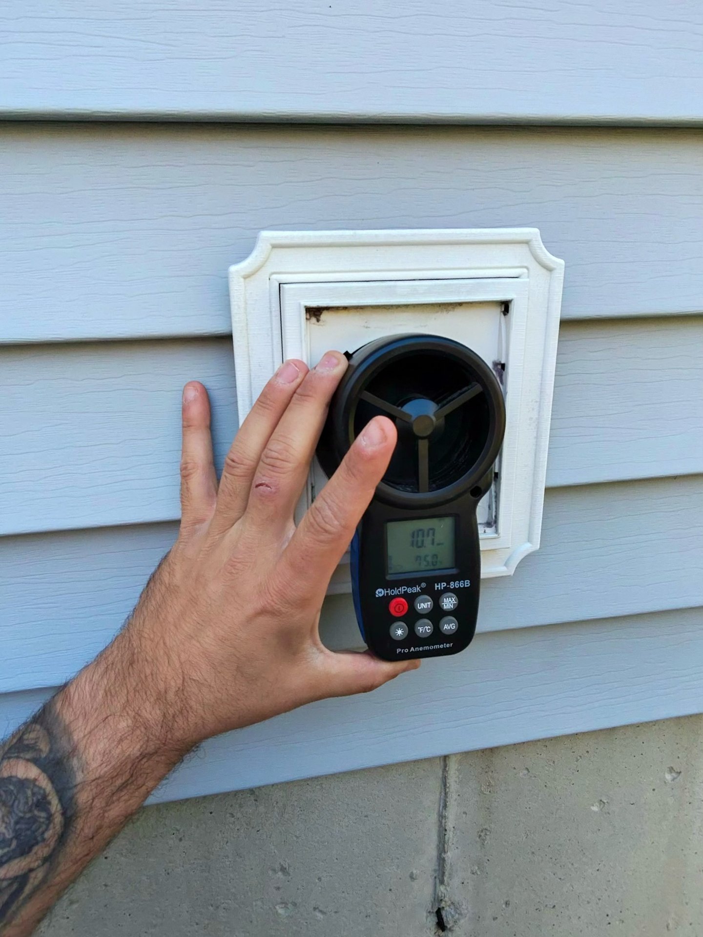 Technician measuring airflow at a wall vent